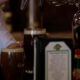 Bartender pours dark stout from a tap into a pint glass at a bar, with another Guinness glass nearby.