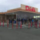 People line up outside a Dick's store, waiting near the entrance with orange cones guiding the line in the parking lot.