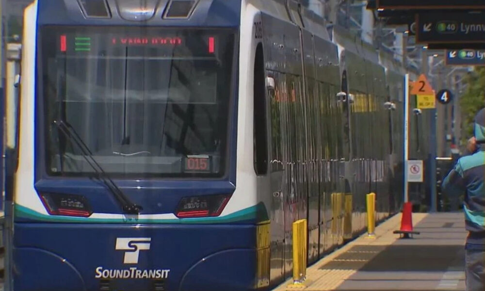 Front view of a blue Sound Transit light-rail train at a station platform with windshield wipers visible on the front window.