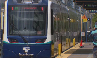 Front view of a blue Sound Transit light-rail train at a station platform with windshield wipers visible on the front window.