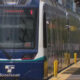 Front view of a blue Sound Transit light-rail train at a station platform with windshield wipers visible on the front window.