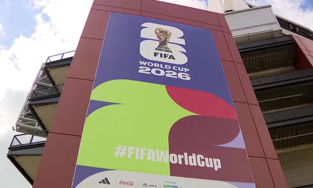 Large FIFA World Cup 2026 banner on a stadium exterior with colorful abstract shapes and the hashtag #FIFAWorldCup on it.