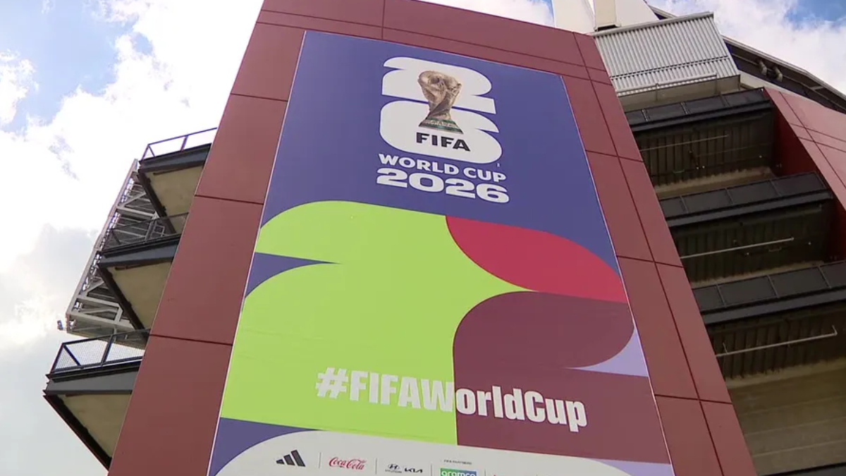 Large FIFA World Cup 2026 banner on a stadium exterior with colorful abstract shapes and the hashtag #FIFAWorldCup on it.