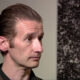 Man with slicked-back hair in a close-up profile during an interview setting