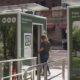 Portable restroom trailer labeled Free Restroom; a person is entering the unit while a worker in a reflective vest stands nearby.