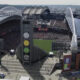 Aerial view of a packed outdoor stadium during a game, with a tall tower displaying colored circular panels in the foreground.