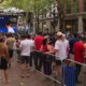 Crowd gathered behind metal barricades watching a large outdoor screen at a street event in Pioneer Square.