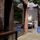 Urban sidewalk scene with brick storefronts and a blue sidewalk sign in front of a cafe/bar named 'Barnacle'.