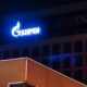 Blue Gazprom sign glowing on a dark building at night, with neon-lit foreground edge.