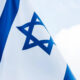 Israeli flag waving in the wind, blue stripes and a central Star of David.