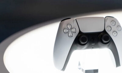 White PlayStation 5 DualSense wireless controller facing forward, with joysticks and buttons visible against a soft background.