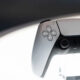 White PlayStation 5 DualSense wireless controller facing forward, with joysticks and buttons visible against a soft background.