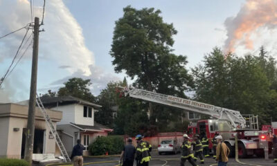 Seattle Fire Department uses an aerial ladder to reach a two-story house as firefighters work on a residential street.