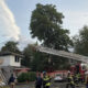 Seattle Fire Department uses an aerial ladder to reach a two-story house as firefighters work on a residential street.
