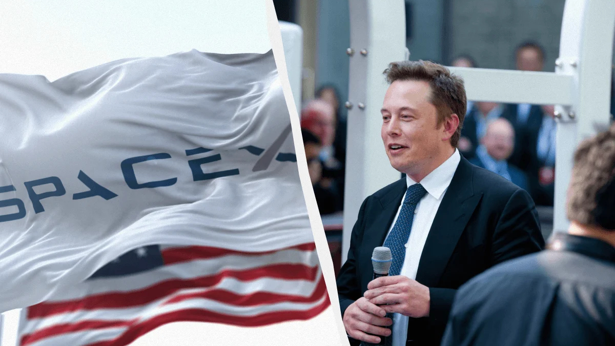 Elon Musk in a suit speaking into a microphone at a SpaceX event, with a SpaceX flag in the foreground.