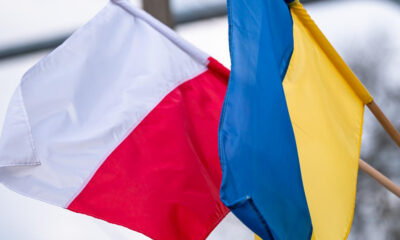 Polish flag (white over red) and Ukrainian flag (blue over yellow) fluttering side by side in the wind.