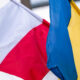 Polish flag (white over red) and Ukrainian flag (blue over yellow) fluttering side by side in the wind.