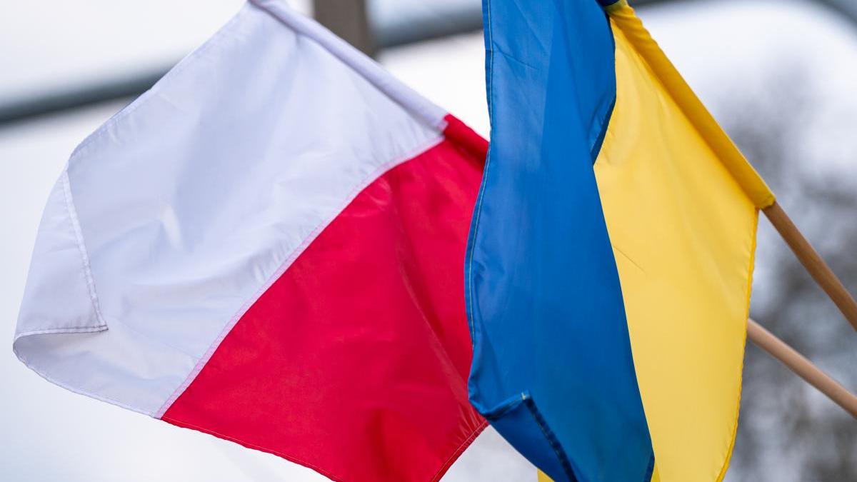 Polish flag (white over red) and Ukrainian flag (blue over yellow) fluttering side by side in the wind.