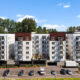 Modern multi-story apartment building with white and brown facade, balconies, and a parking lot in front.