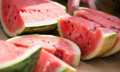 Sliced ripe watermelon on a cutting board, showing pink flesh and black seeds in the fruit's interior.