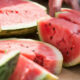 Sliced ripe watermelon on a cutting board, showing pink flesh and black seeds in the fruit's interior.