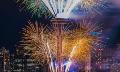 Fireworks explode around the Space Needle against a nighttime Seattle skyline.