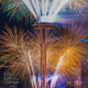 Fireworks explode around the Space Needle against a nighttime Seattle skyline.