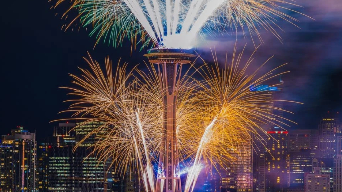Fireworks explode around the Space Needle against a nighttime Seattle skyline.