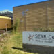 Exterior of STAR Center in Metro Parks Tacoma, beige building with a star logo and a large sign in the foreground reading 'STAR Center Metro Parks Tacoma'.