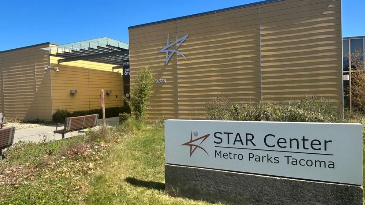 Exterior of STAR Center in Metro Parks Tacoma, beige building with a star logo and a large sign in the foreground reading 'STAR Center Metro Parks Tacoma'.