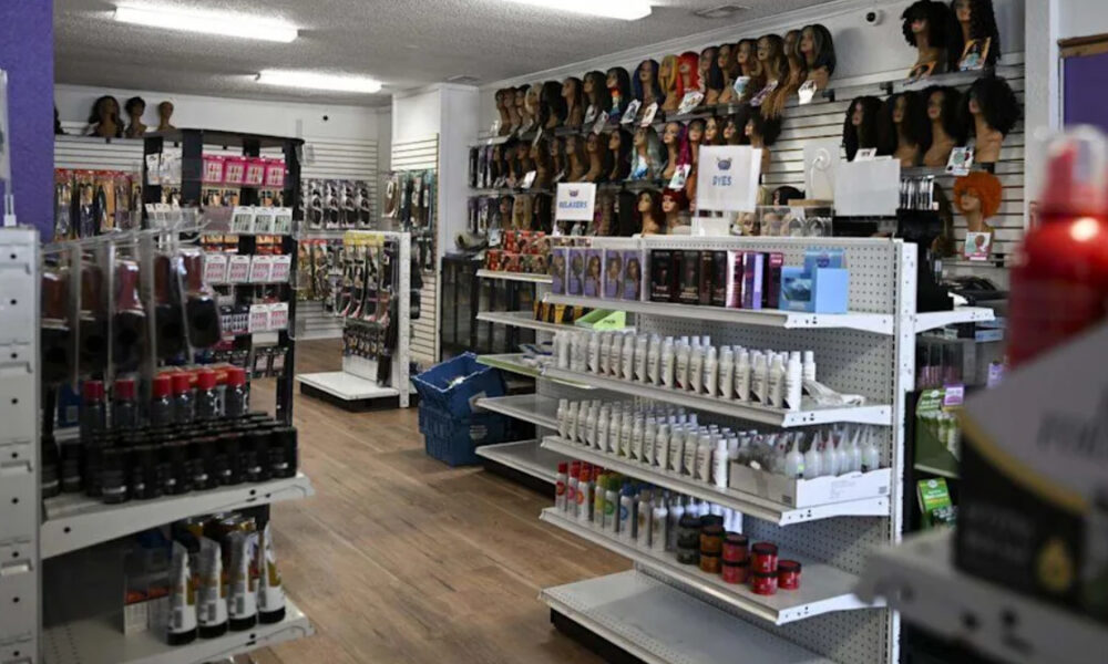 Interior of a beauty supply store with wig displays and shelves of hair products along the aisle.