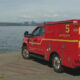 Red emergency rescue vehicle parked by a lake with the city skyline in the distance, labeled 5 Battalion on the side and back.