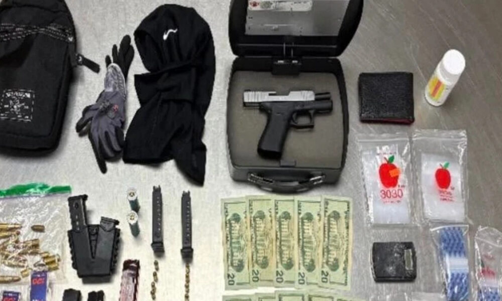 Gun in a hard case with magazines, gloves, and clothing laid out alongside cash and small packets on a gray floor.