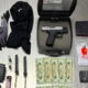 Gun in a hard case with magazines, gloves, and clothing laid out alongside cash and small packets on a gray floor.