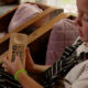 Child in striped overalls sits on a couch, holding a beige remote and pressing a button.