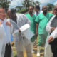 Group of volunteers in protective gowns outside clinic; one man helps another adjust his gown.