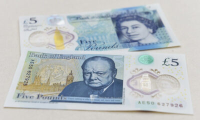 Two five-pound Bank of England notes laid flat, one with an image of Winston Churchill and the other showing Queen Elizabeth II on the reverse side? No, the note with Churchill is front-facing.
