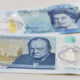 Two five-pound Bank of England notes laid flat, one with an image of Winston Churchill and the other showing Queen Elizabeth II on the reverse side? No, the note with Churchill is front-facing.