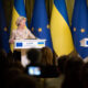 Two officials speak at separate podiums during a press conference with EU and Ukrainian flags behind them in Kyiv.