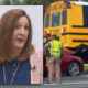 Woman being interviewed in the foreground while a yellow school bus crash with responders is visible in the background.