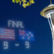 Night scene in Seattle with the Space Needle; a bright LED scoreboard shows FINAL 9-9 under a starry sky.