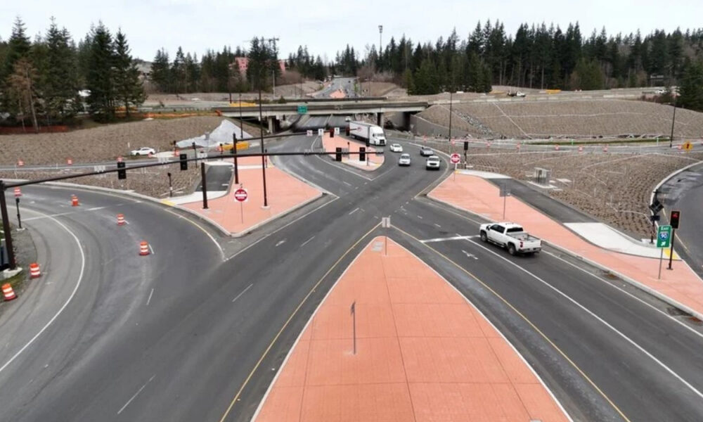 Aerial view of a multi-lane road intersection under construction with orange pedestrian islands and traffic cones separating traffic.