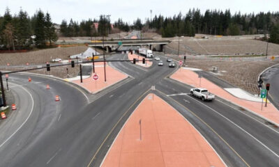 Aerial view of a multi-lane road intersection under construction with orange pedestrian islands and traffic cones separating traffic.