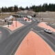 Aerial view of a multi-lane road intersection under construction with orange pedestrian islands and traffic cones separating traffic.