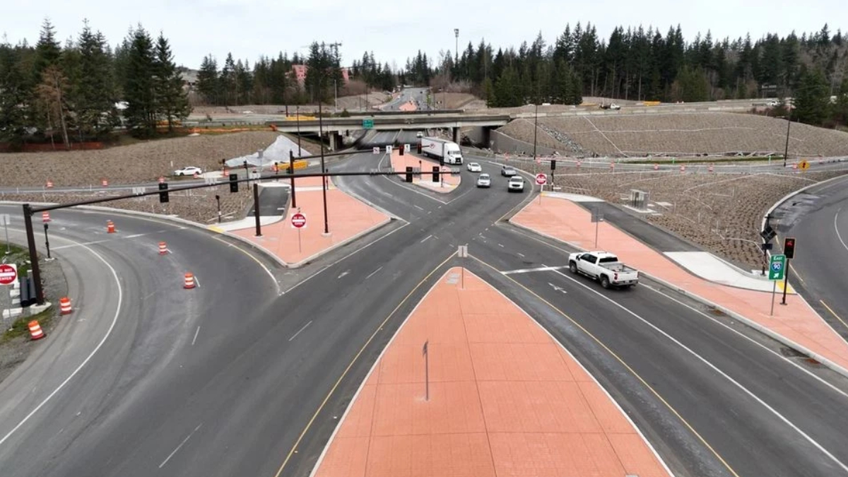 Aerial view of a multi-lane road intersection under construction with orange pedestrian islands and traffic cones separating traffic.