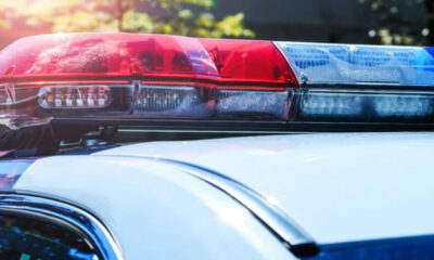 Red and blue police lights on top of a patrol car, flashing in daylight