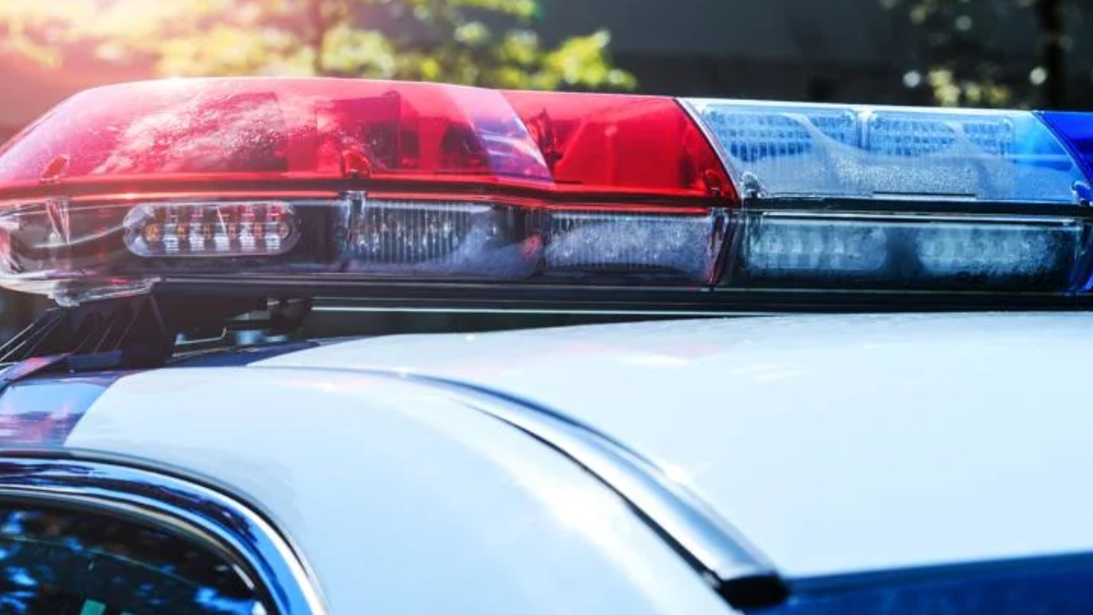 Red and blue police lights on top of a patrol car, flashing in daylight