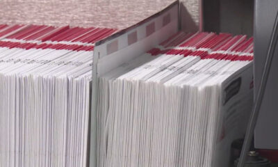 Rows of white documents with red header tabs neatly stacked in a filing bin, ready for processing