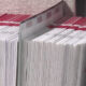 Rows of white documents with red header tabs neatly stacked in a filing bin, ready for processing