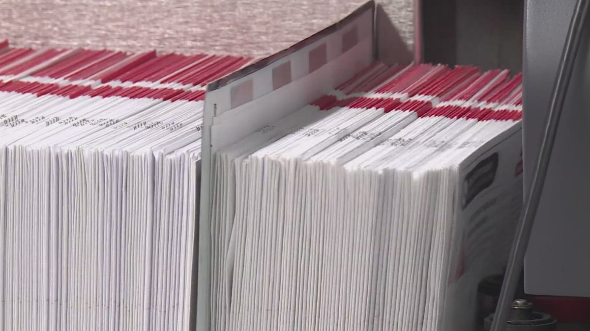 Rows of white documents with red header tabs neatly stacked in a filing bin, ready for processing